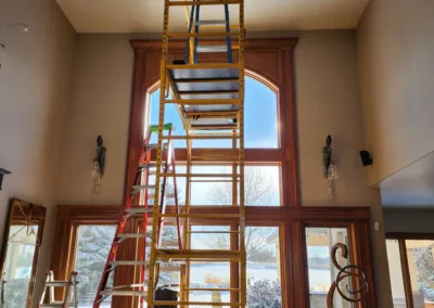 A ladder is in the middle of a room with a window.