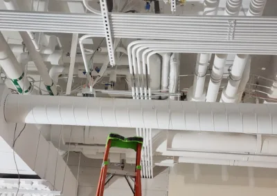 A ladder is being used to install pipes in a room.