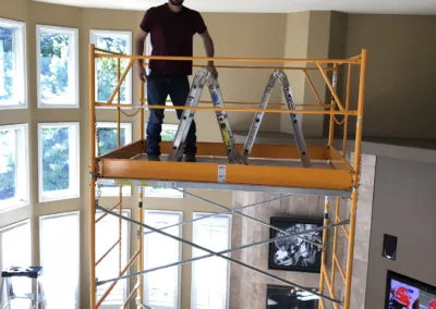 A man standing on a scaffold in a living room.